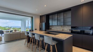Una cocina moderna con una isla grande, taburetes de bar y vistas al exterior.