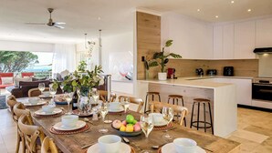 A modern dining area with a wooden table set for a meal, surrounded by wooden chairs. - Classic Charm Meets Modern Comfort at Atlantic Pearl (Cape Town)