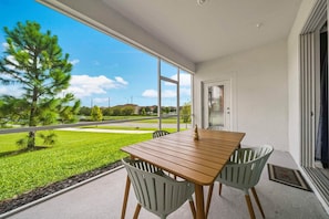 Un balcon avec une table et des chaises en bois, une vue sur un paysage verdoyant et un ciel dégagé.