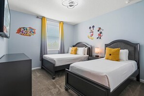 Ein Hotelzimmer mit zwei Einzelbetten, einem Schreibtisch, einem Stuhl, einem Fernseher und einem Fenster mit Vorhängen.