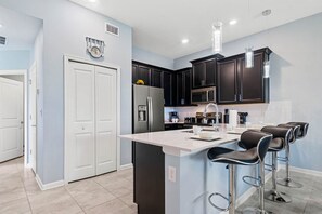 A modern kitchen with dark cabinets, a central island, and bar stools.