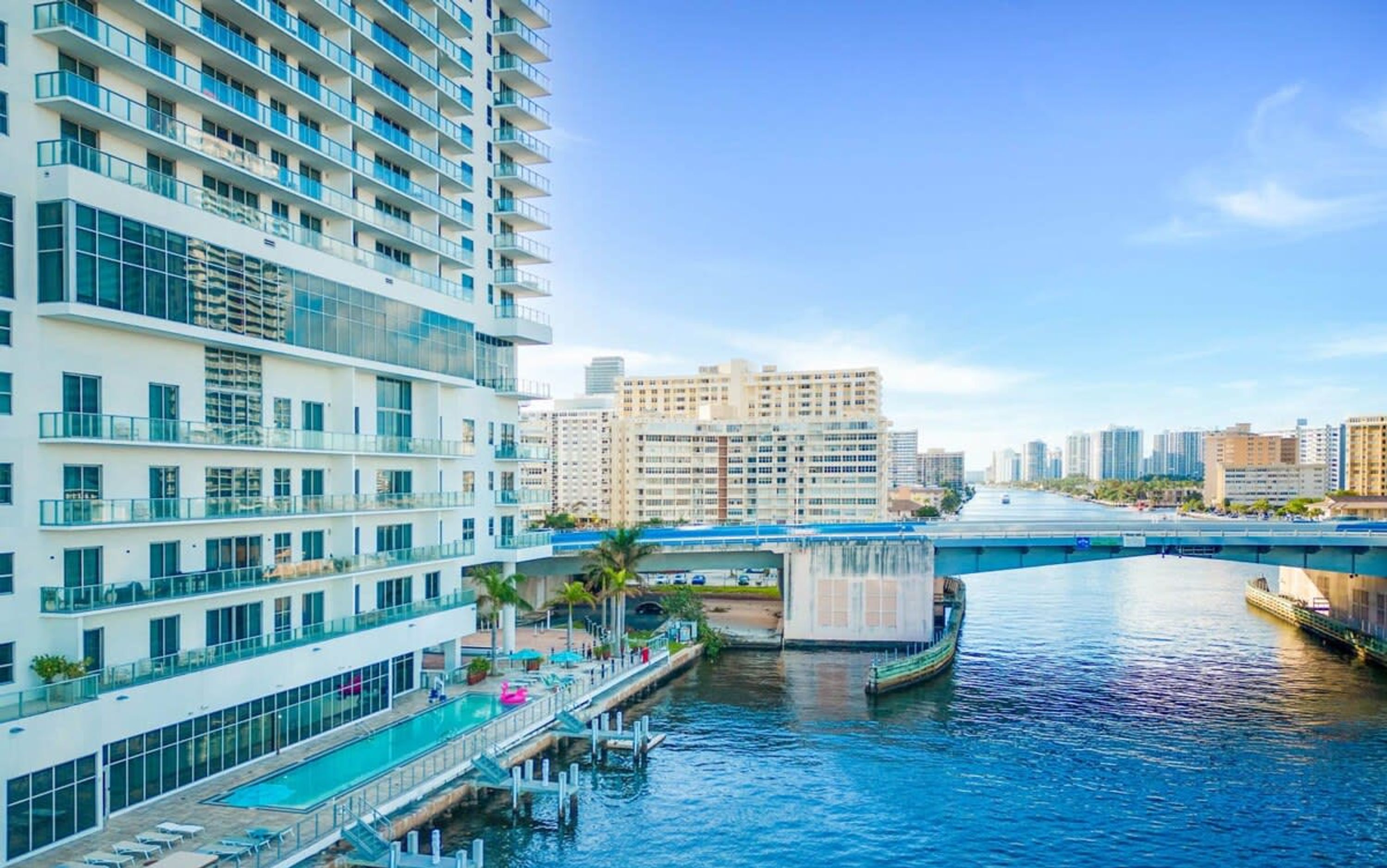 A high-rise hotel with a rooftop pool, waterfront views, and a bridge in the background.