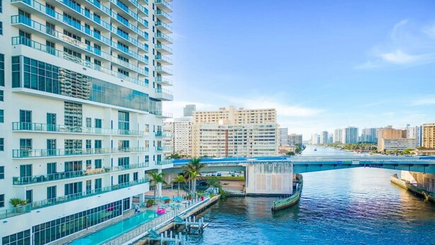 A high-rise hotel with a rooftop pool, waterfront views, and a bridge in the background. - 1 BR Apartment With Bay View and Parking Included (Hollywood)