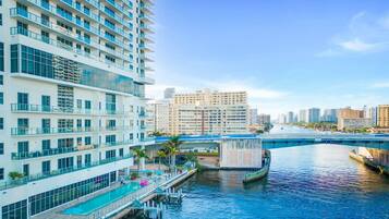 A high-rise hotel with a rooftop pool, waterfront views, and a bridge in the background.