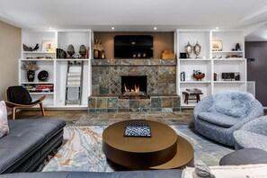 A modern living room with a fireplace, a sofa, a chair, and a round coffee table.