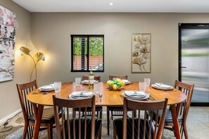 Un coin repas comprenant une table ronde en bois, six chaises et un élément décoratif mural.