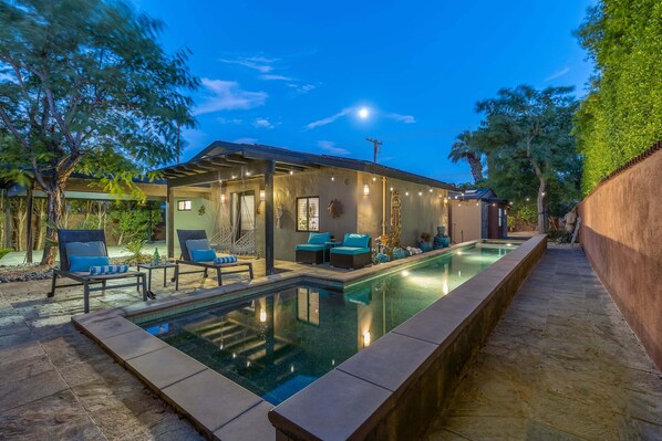A modern house with a swimming pool, outdoor seating, and a covered patio area.