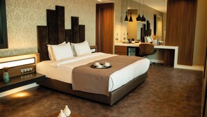 A modern hotel room with a large bed, bedside table, and a desk area with a chair. - Sam Royal Hotel (Eskisehir)