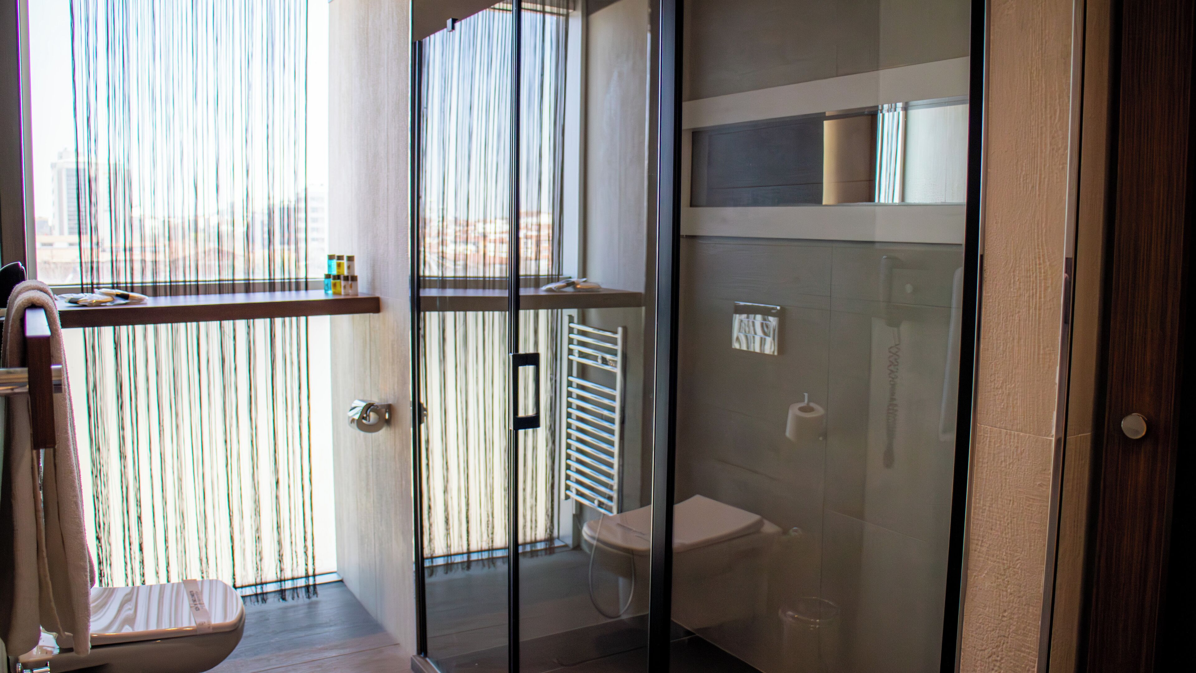 Et moderne badeværelse med en glasbrusekabine, toilet og håndklædestang.