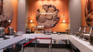 A buffet setup with various food items and a large wall mural. - Sam Royal Hotel (Eskisehir)