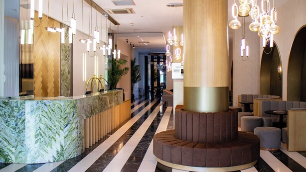 A modern hotel lobby with a reception desk, seating area, and decorative lighting. - Sam Royal Hotel (Eskisehir)