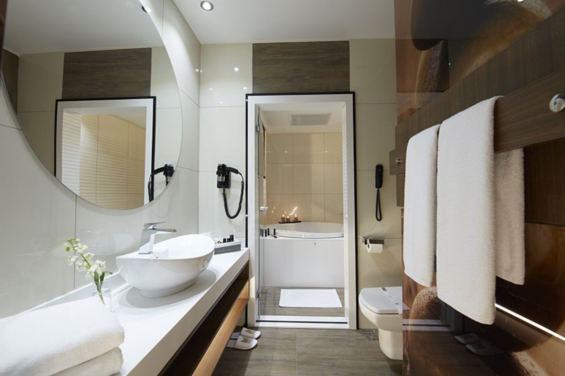 A modern bathroom with a large sink, a bathtub, and a toilet. There is a mirror above the sink and a towel rack on the wall.