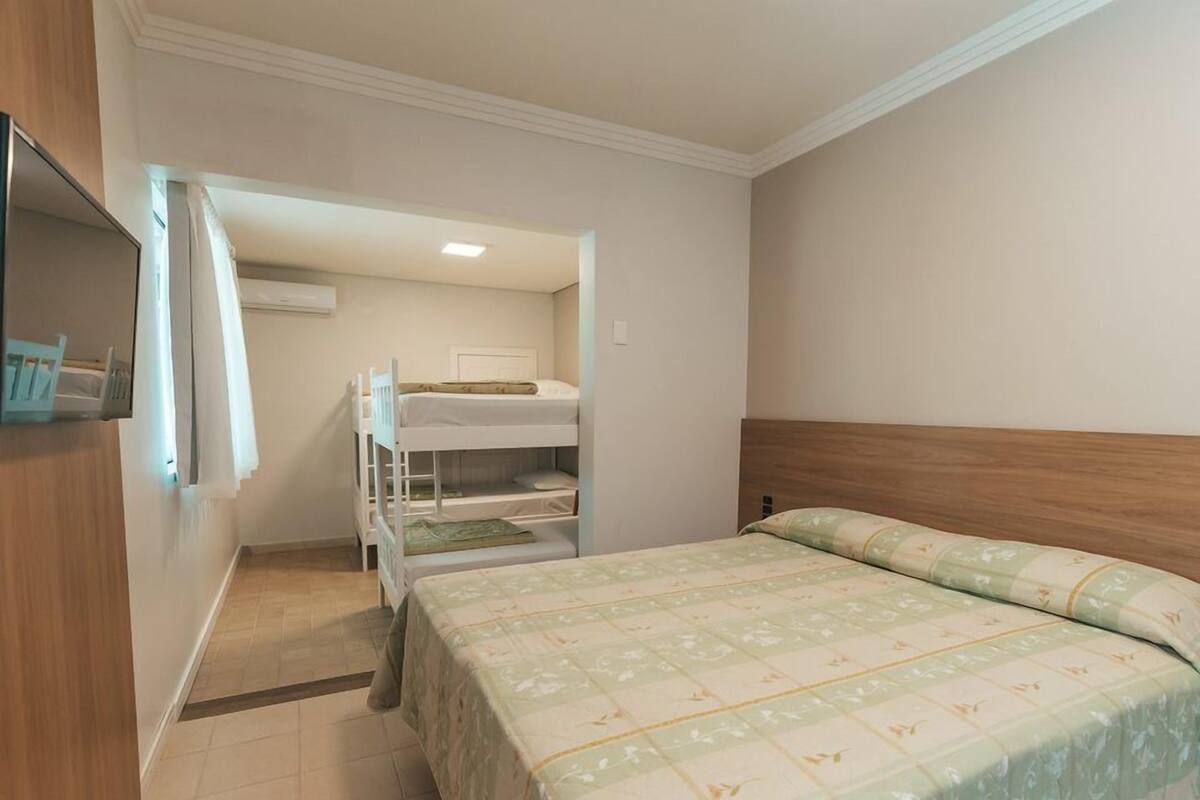 A room with a bunk bed, a single bed, and a wooden headboard.