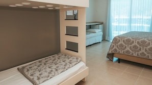 A room with a bunk bed, a desk with a chair, and a bed with a patterned bedspread. - Villa Di Acqua Hotel (Gaspar)