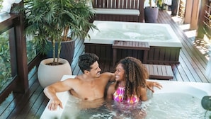 A couple relaxing in a hot tub on a wooden deck with potted plants. - Villa Di Acqua Hotel (Gaspar)