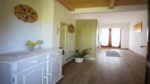 Una habitación amplia con techo de madera, un tocador blanco con cajones, un espejo y una planta en maceta.