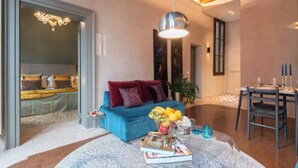 Ein modernes Wohnzimmer mit einem blauen Sofa, einem Essbereich mit Tisch und Stühlen sowie einer Kronleuchter.