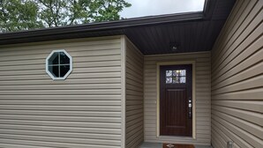 A single-story building with beige siding, a dark brown front door, and a small window with a white frame.