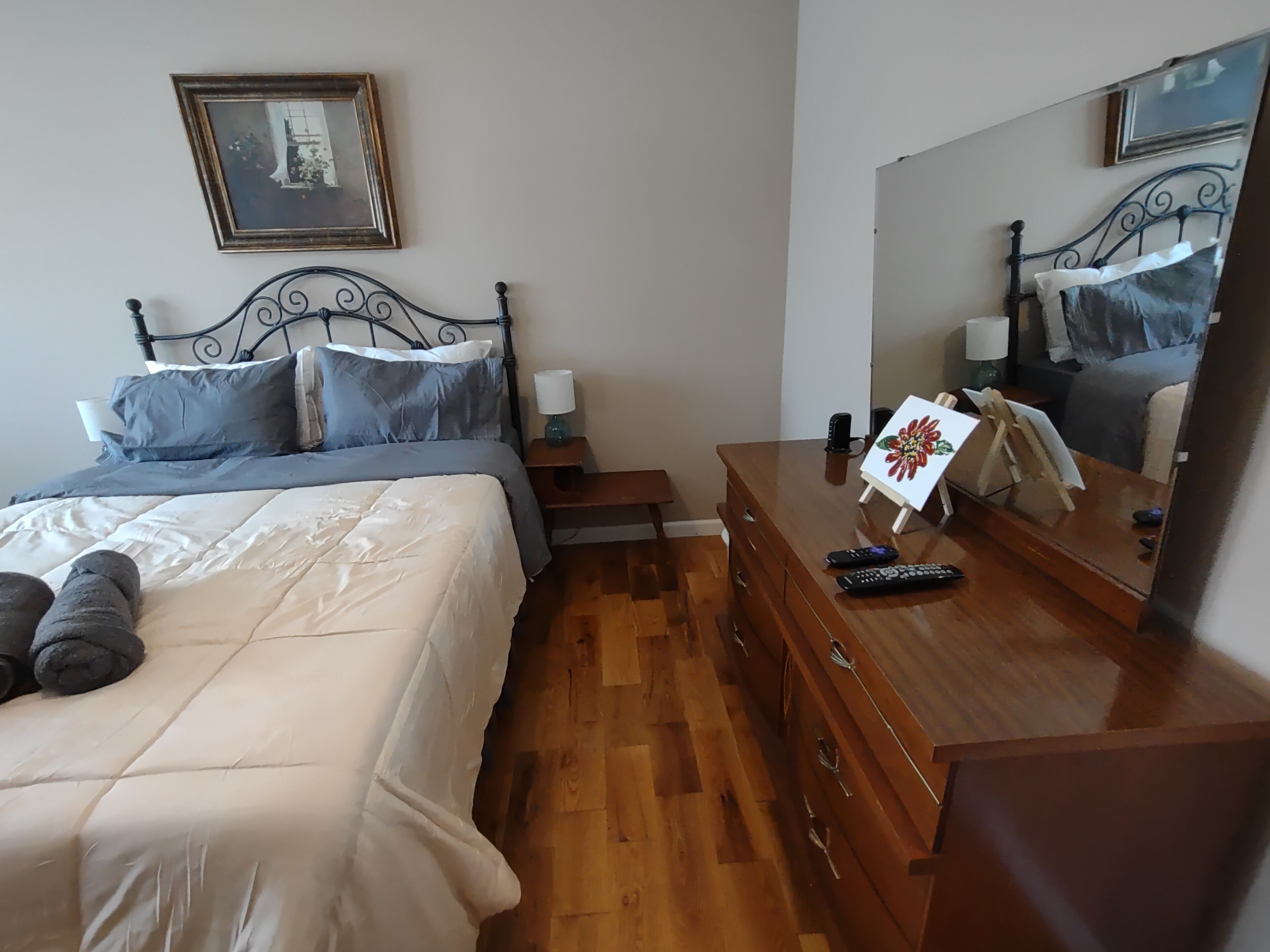 Una camera da letto con un letto, una cassettiera, un comodino e un grande specchio.