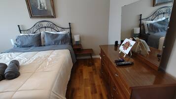 Una camera da letto con un letto, una cassettiera, un comodino e un grande specchio.