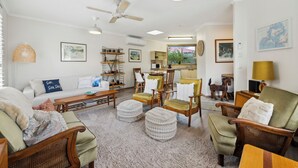 Un salon spacieux comprenant un canapé, des fauteuils, une table basse et un ventilateur de plafond.