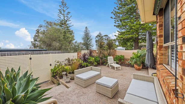 Une terrasse avec des meubles d’extérieur, une pergola et diverses plantes.