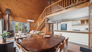 Un intérieur en bois comprenant un coin repas, une cuisine et un escalier menant à un niveau supérieur.