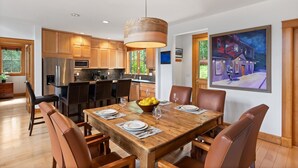 A modern kitchen with wooden cabinets, stainless steel appliances, and a dining area with a wooden table and leather chairs. - Polecat Chalet 4 Bedroom Home by RedAwning (Telluride)