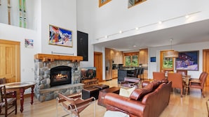 A spacious living area with a stone fireplace, leather sofa, and a dining table. - Polecat Chalet 4 Bedroom Home by RedAwning (Telluride)