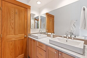 Une salle de bain avec deux lavabos, des meubles en bois et un grand miroir.