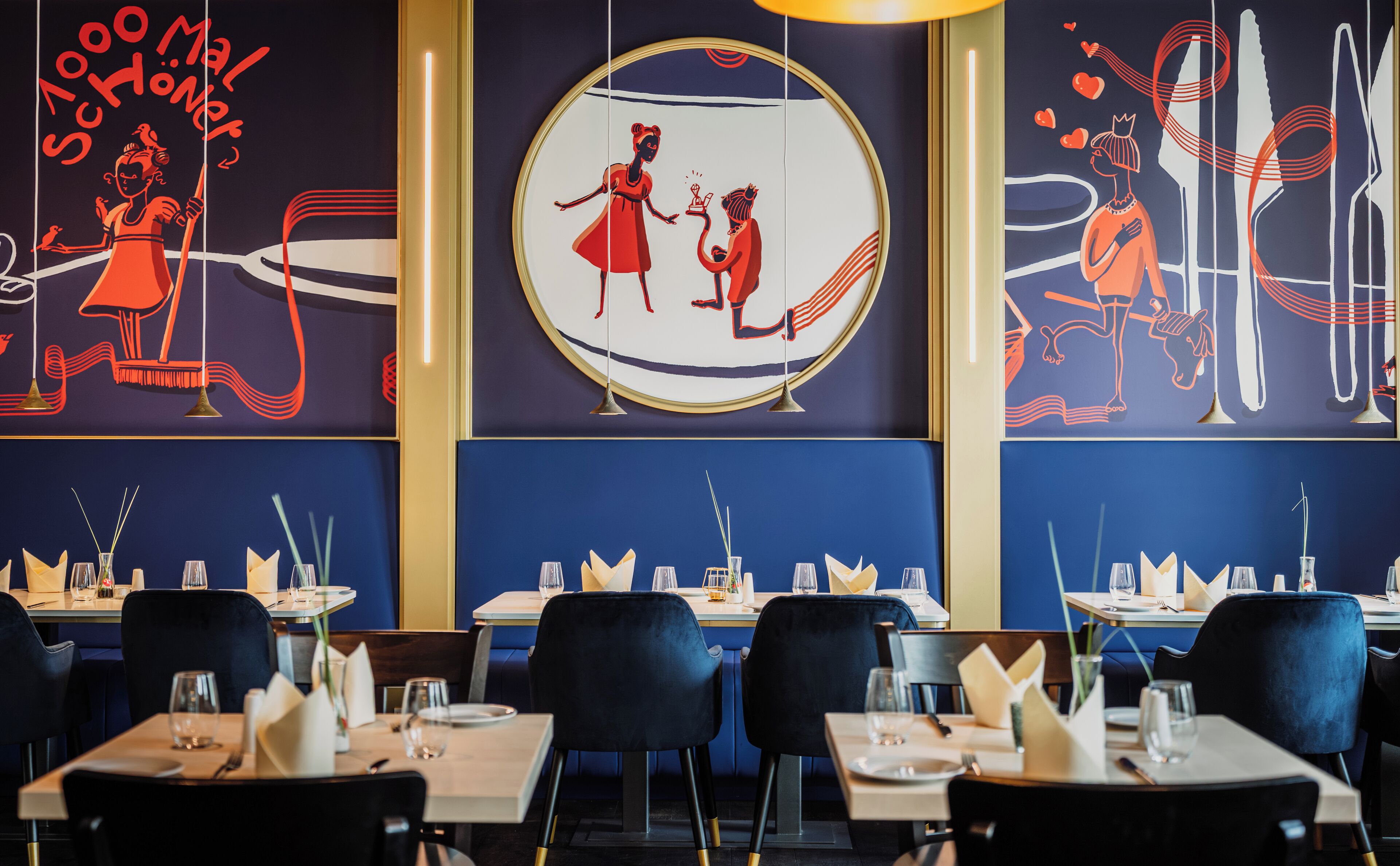 A restaurant interior with tables set for dining, featuring artwork on the walls and a modern design.