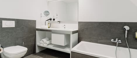 Un baño moderno con inodoro, lavamanos, espejo y bañera.