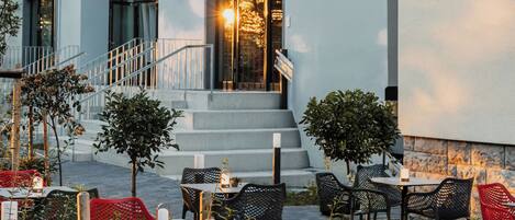 A hotel exterior with outdoor seating, a staircase, and a sign reading "Fiume Hotel".