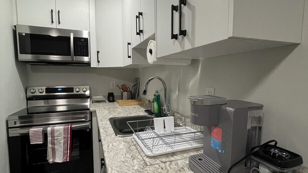 Una cocina moderna con armarios blancos, electrodomésticos de acero inoxidable y una encimera de mármol.
