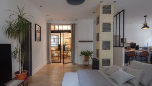 A modern living room with a sofa, a coffee table, and a dining area with a kitchen in the background. - Spacious appartment in the heart of Angers - 6 PAX (Angers)
