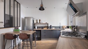 A modern kitchen with a wooden island, bar stools, and a built-in stove. - Spacious appartment in the heart of Angers - 6 PAX (Angers)