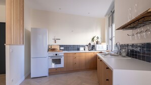 A modern kitchen with wooden cabinets, a white refrigerator, an oven, and a sink. - Spacious appartment in the heart of Angers - 6 PAX (Angers)