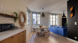 A modern kitchen with wooden cabinets, a dining area with a round table, and a blue sofa. - Spacious appartment in the heart of Angers - 6 PAX (Angers)