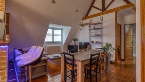 Ein gemütliches Loft-Zimmer mit Holztisch, gepolsterten Sitzbänken und einer hohen Decke mit freiliegenden Balken.