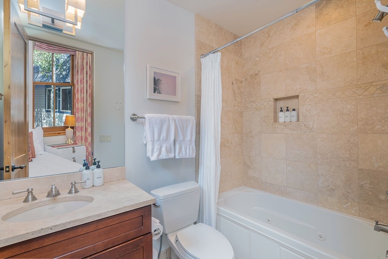 A bathroom with a bathtub, toilet, sink, and a shower curtain.