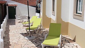 En fliseterrasse med liggestole og en stor parasol.