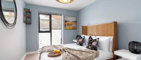 A bedroom with a bed, bedside table, and a window with blinds.