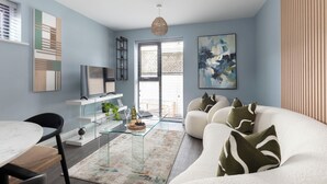 A modern living room with a sofa, a glass coffee table, and a TV on a white stand. - Beautiful 2 Bedroom Apartment With Parking in The Docks (Gloucester)