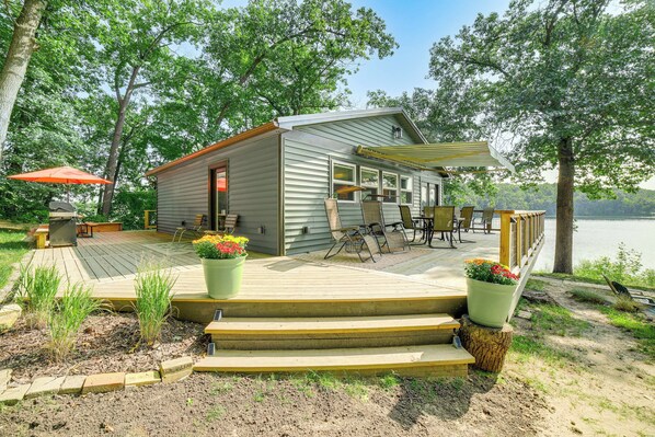Une cabane dotée d’une terrasse, de meubles de jardin et offrant une vue sur le lac.
