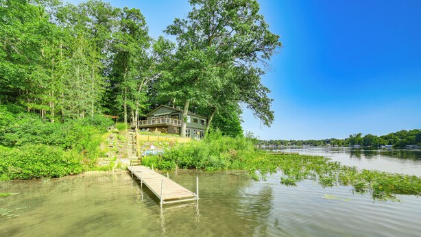 Una casa sul lago con un molo di legno che vi conduce.