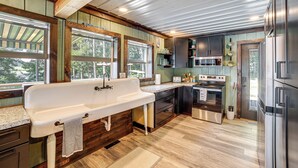 Una cucina con un lavandino grande bianco, pensili in legno e un frigorifero in acciaio inossidabile.