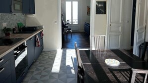 Une cuisine moderne avec des meubles de couleur sombre, un plan de travail en bois et un sol à motifs.