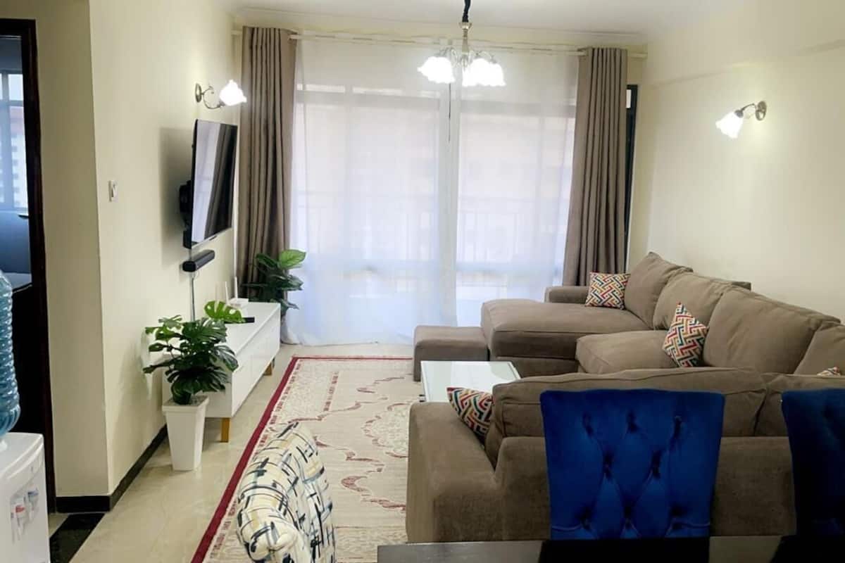 Een moderne woonkamer met een zithoek, een salontafel en een aan de muur bevestigde televisie.