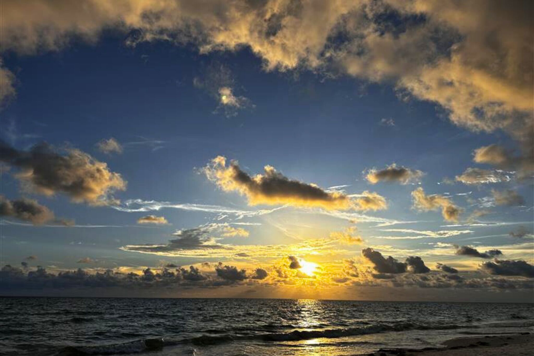 Un atardecer sobre el océano con nubes.
