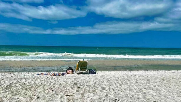 A beach with a chair and a blanket on the sand, and the ocean in the background. - Romantic Island Getaway! Just Steps from the Beach (Bradenton Beach)